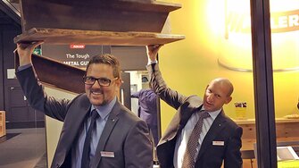 Täuschend echt: ADLER-Verkaufsleiter Daniel Pesserer und Verkaufsprofi Christian Schütz nehmen den „Stahlträger“ aus lackiertem Holz auf die leichte Schulter.