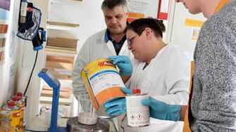 ADLER Schulungsprofi Hans-Peter Thaler (li.) zeigt Schülern der FH Salzburg, worauf es beim Lackieren ankommt.