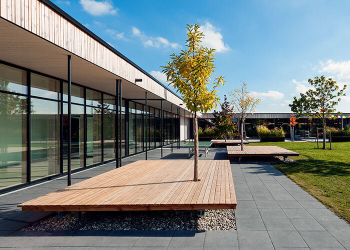 Durchgehende Fensterfronten verbinden die eingeschoßige Schule mit dem grünen Pausen- und Spielhof (Foto: Antje Hanebeck)